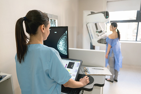 Woman getting a mammogram with a female health care provider at the computer