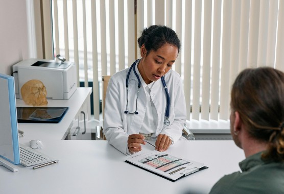 Female doctor talking to male patient at a table in a medical office