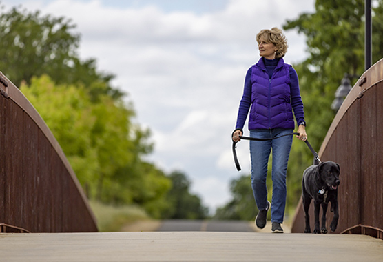 Woman walking her dog on a bridge.