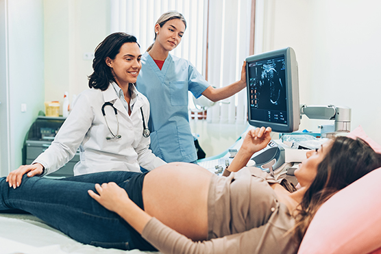Pregnant woman getting an ultrasound with physician and nurse next to her