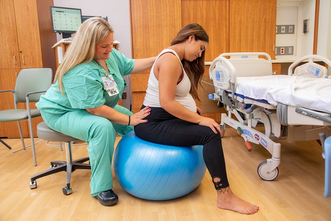 Nurse applying pressure with her hand on pregnant woman’s hip to relieve pain