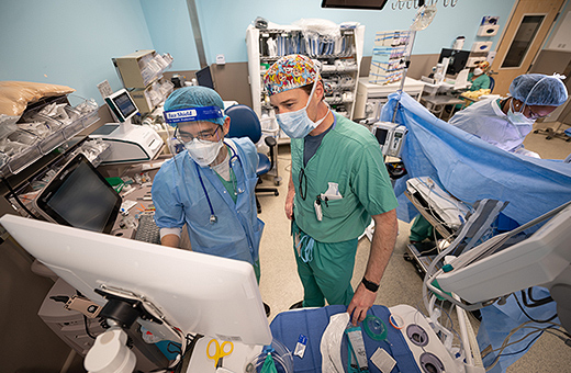 Two health care providers looking at screen during surgery.