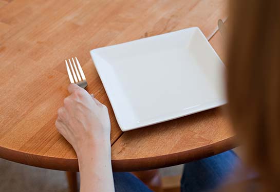 A person sitting in front of an empty plate at a table