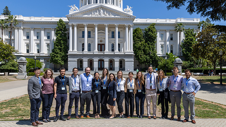 Fifteen students from various medical schools stand in front of the California Capitol before touring the building