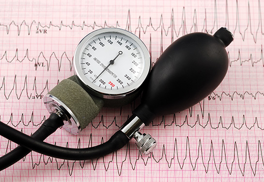 blood pressure instrument resting on a heart chart