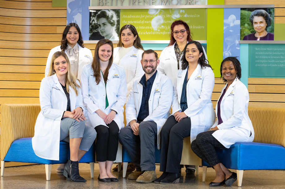 group of clinicians in white coat stand and sit side-by-side to pose for camera