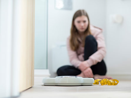 girl sitting on the floor looking at a scale