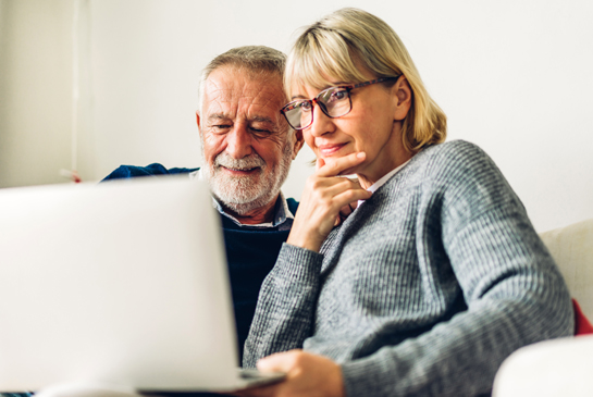 An older couple looks at their laptop