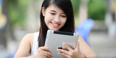 Girl on iPad sitting outside. (C) UC Regents. All rights reserved.