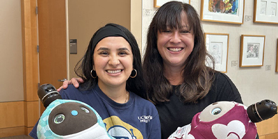 Two women holding robots and smiling (c) UC Davis Regents. All rights reserved.