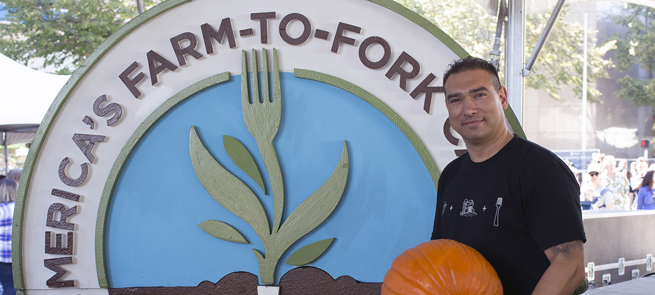 Chef Santana Diaz next to a Farm-to-Fork sign