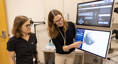 Debra Kahn (left) and Katharine Marder (right) view an image on the transcranial magnetic stimulation device
