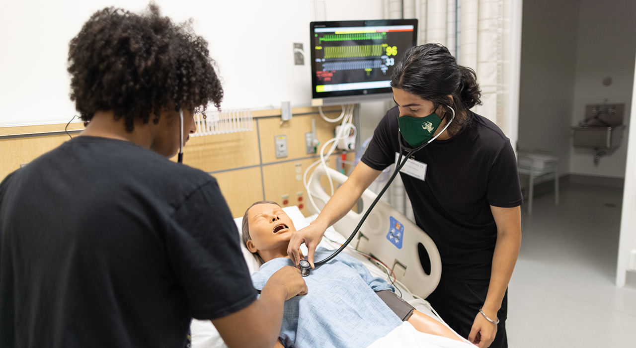 Levert Bryant, left, and a fellow SHINES participant get hands-on experience in a hospital manikin simulation.