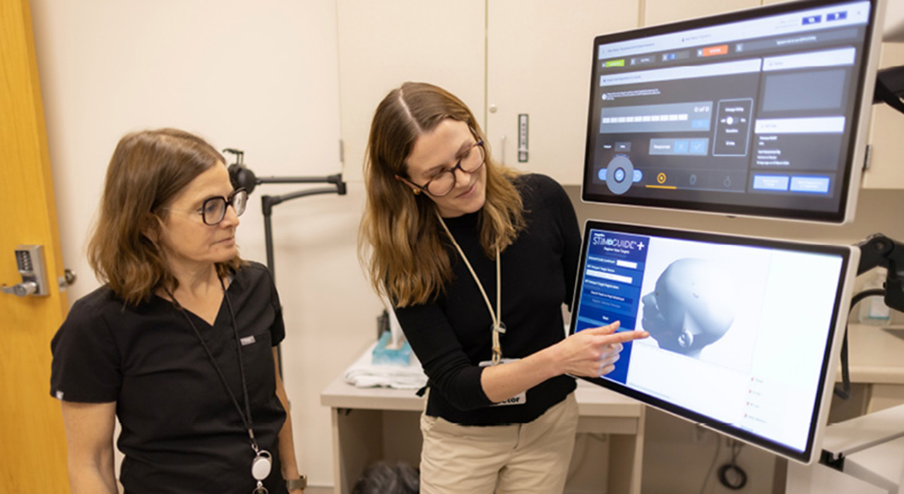 Debra Kahn (left) and Katharine Marder (right) view an image on the transcranial magnetic stimulation device.