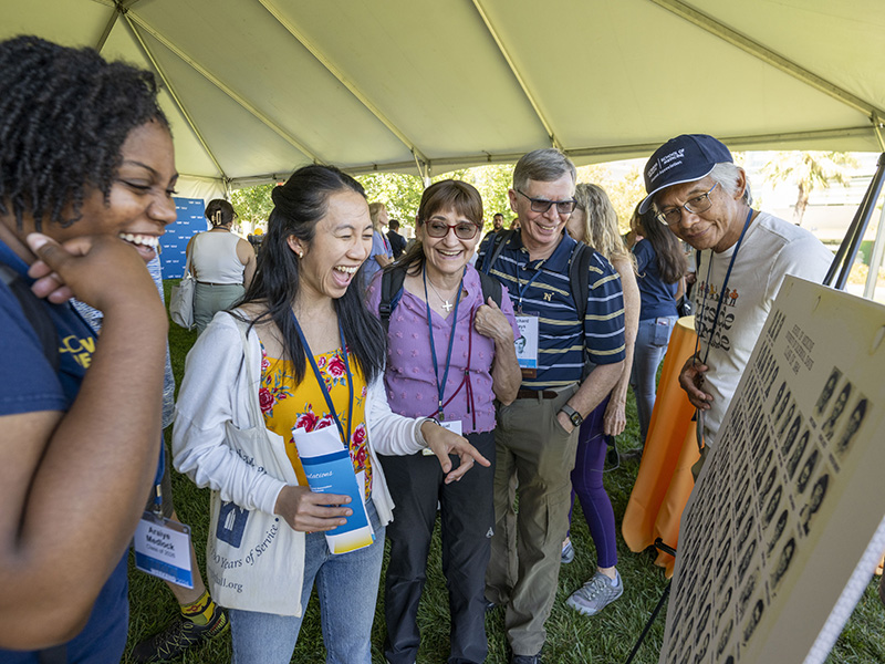 Ben Mandac (M.D. ’84), Richard Hays (M.D. ’84) and Raquel Hays and students share some laughter as they look through a class composite.