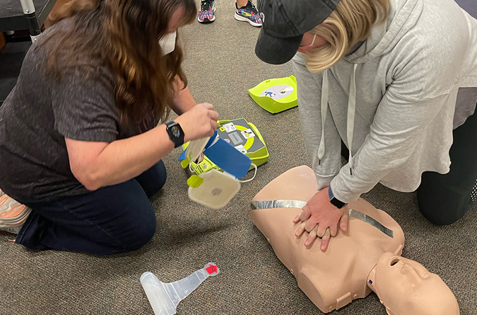 Two women in training for hands-on CPR and use of an AED