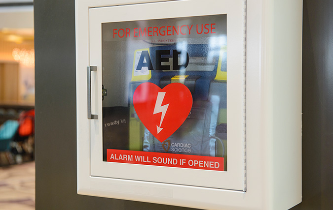 Photo of an AED mounted on wall in a school hallway