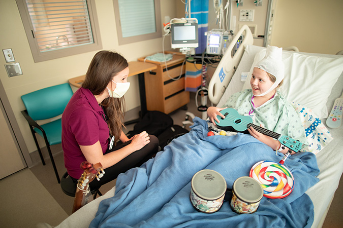 Child Life and Creative Arts Therapy worker doing music therapy with child patient