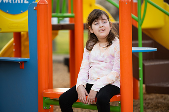 Avery sitting on a playground