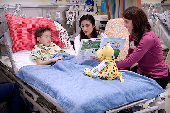 Child life specialists providing support for a pediatric patient in a hospital bed