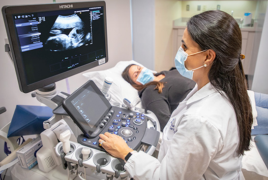 Cardiologist performing fetal echocardiography on pregnant mom