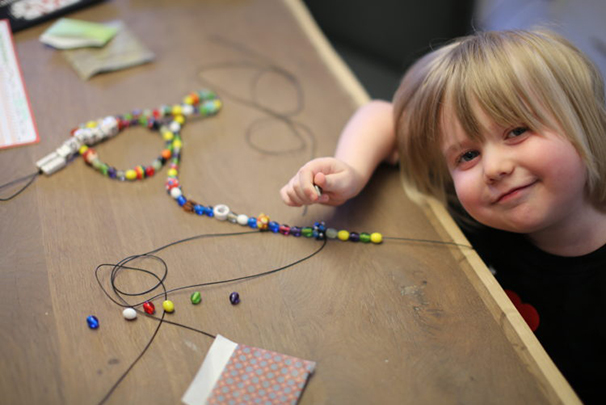 Child making bead necklace, picture from Beads of Courage