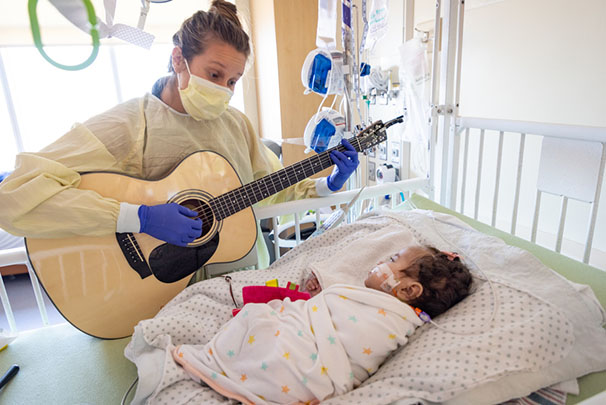 Health care worker playing guitar for infant