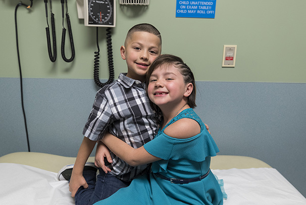 young siblings hugging in hospital room
