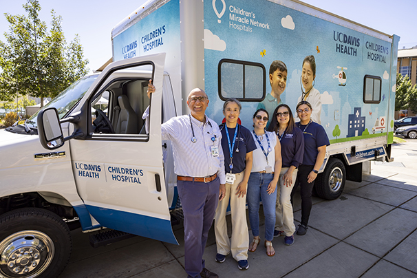 Five members of the uc davis children's hospital team stand beside a van that serves as a mobile clinic