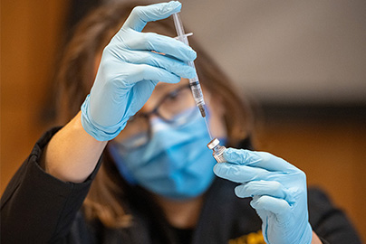 Healthcare worker filling a syringe with vaccine.