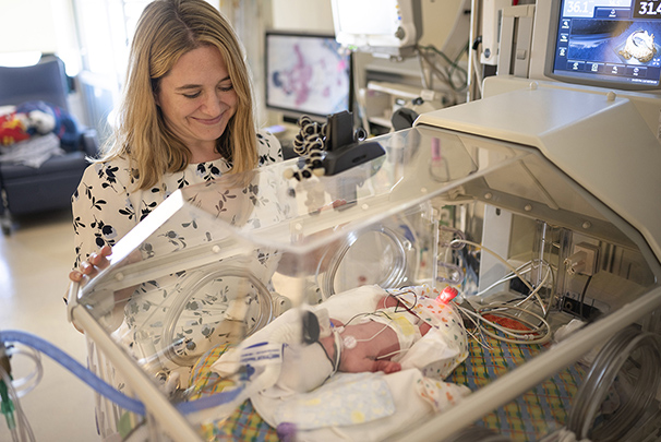 Health care worker smiling at infant using giraffe bed