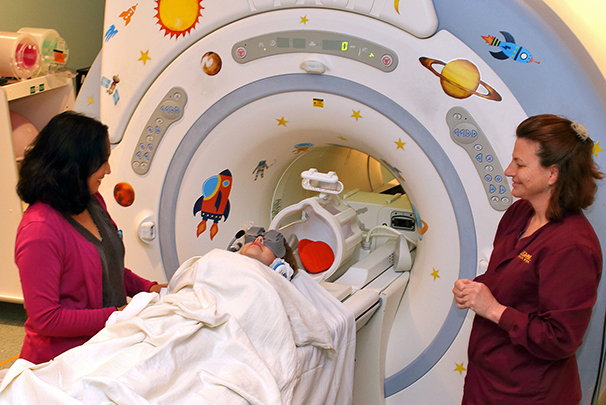 Health care workers assisting child patient using MRI goggles with MRI procedures