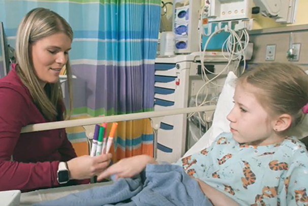 Child life staff holds out colored pens to patient