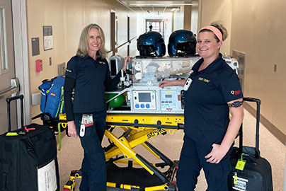 Two neonatal transport team members prepped in a hallway with all their transport gear