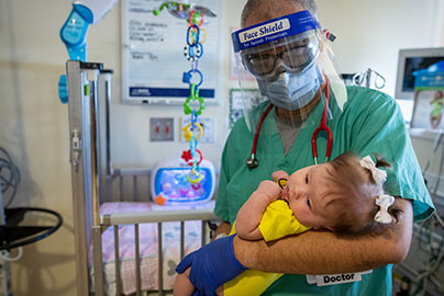 UC Davis neonatalogist holding infant in NICU