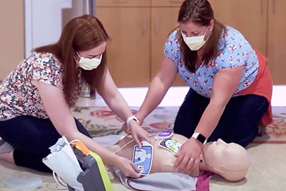 Two women demonstrating how to use an AED