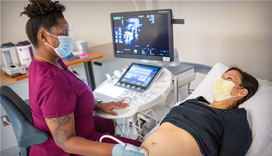 Ultrasound provider performing fetal echocardiogram on expecting mom in private clinic room
