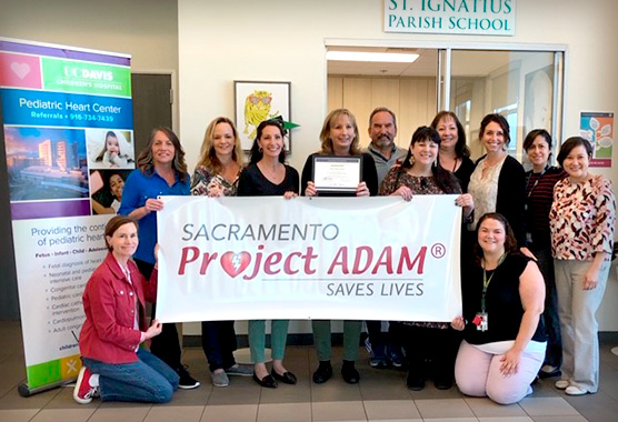 Group of people holding a Project ADAM banner.