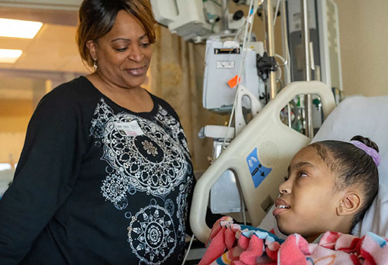 A woman looking down at a child in a hospital bed.