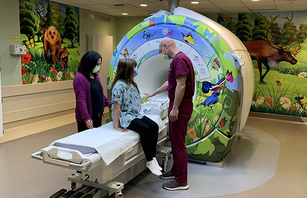 Nurse showing child patient the MRI machine