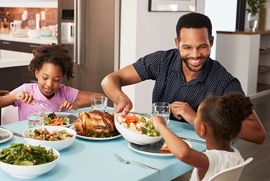 family sitting at dining table eating a healthy meal