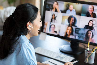 A woman having a virtual meeting in front of her computer with others on her screen