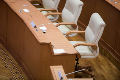 Empty chairs behind desks are seen in a government committee room.