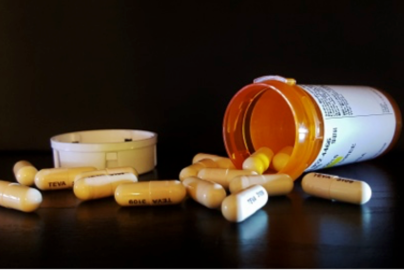 Pills spill out of a pill bottle on its side.