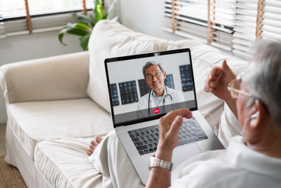 A man speaks with his doctor through a telehealth call on a computer.