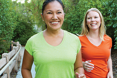 Two women walking outside for exercise, smiling.
