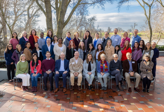 CHPR staff and faculty gather in three rows for a group photo near a river.