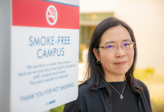 Elisa Tong stand next to a "smoke-free campus" sign. 