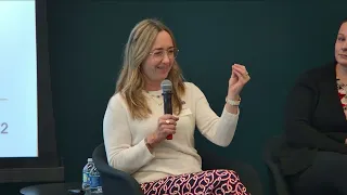 A woman wearing a white shirt and speaks into a microphone.