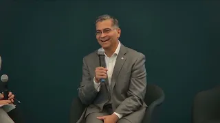 Xavier Becerra speaks into a microphone wearing a dark suit.